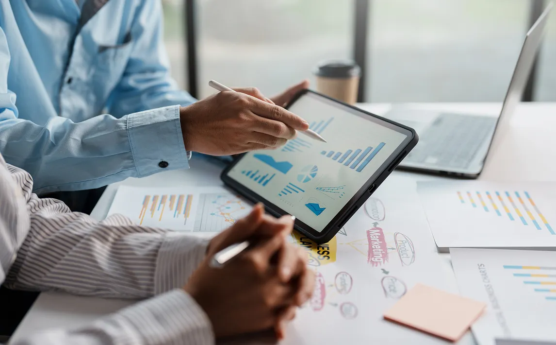 business meeting going over marketing rates on a tablet with various charts