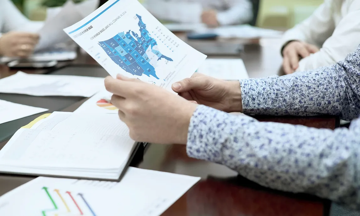 business meeting with someone holding a print-out of the USA map with state ratings